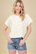 Woman wearing a cream lace top and denim shorts on a beige background