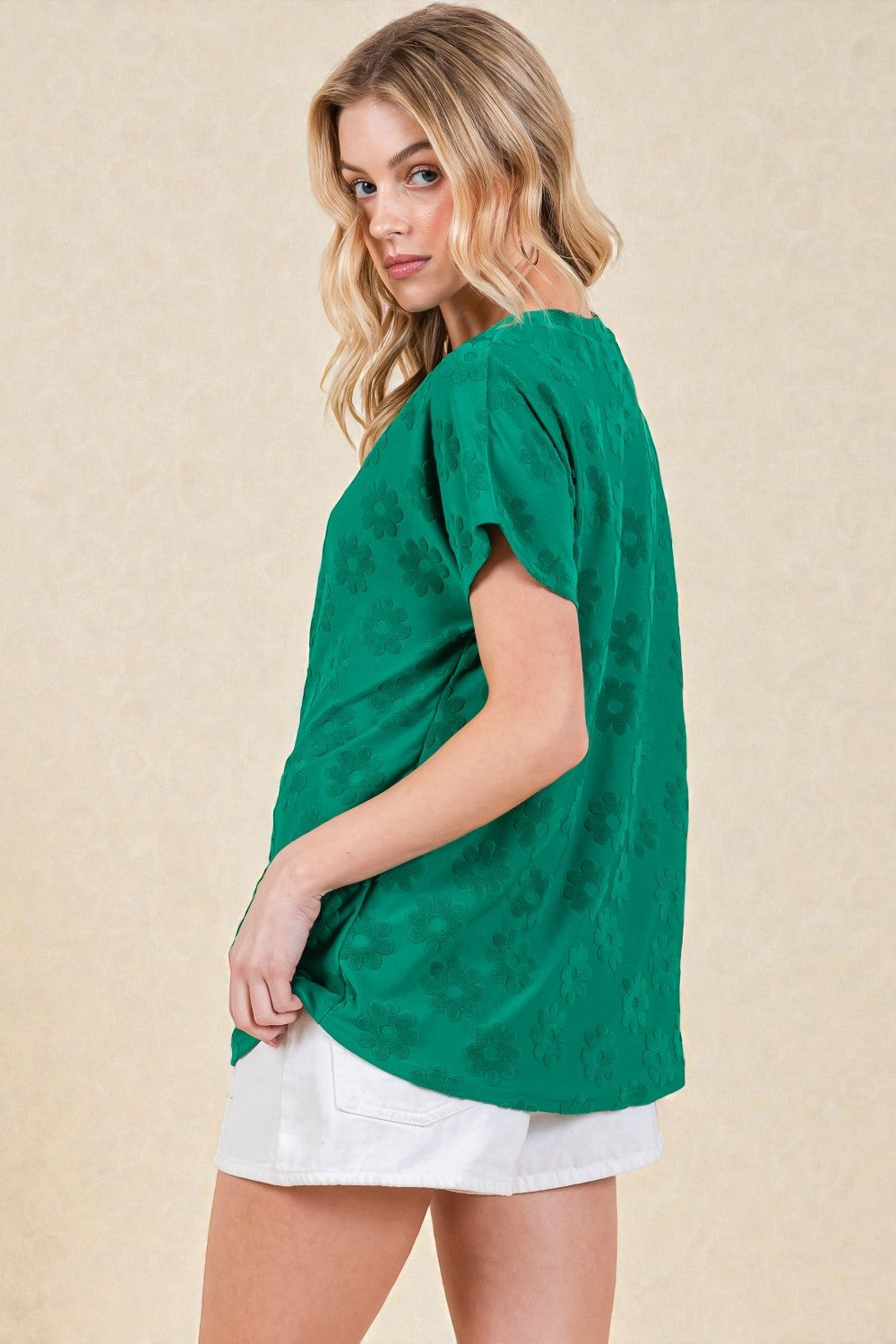 Woman wearing a green top with floral patterns on a beige background