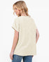 A woman shown from the back wearing a short-sleeve, loose-fitting cream-colored top with a subtle textured pattern, paired with blue jeans, against a plain white background.