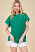 Woman wearing a green patterned top and white shorts on a beige background
