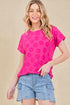 Woman wearing a pink floral top and denim shorts against a beige background