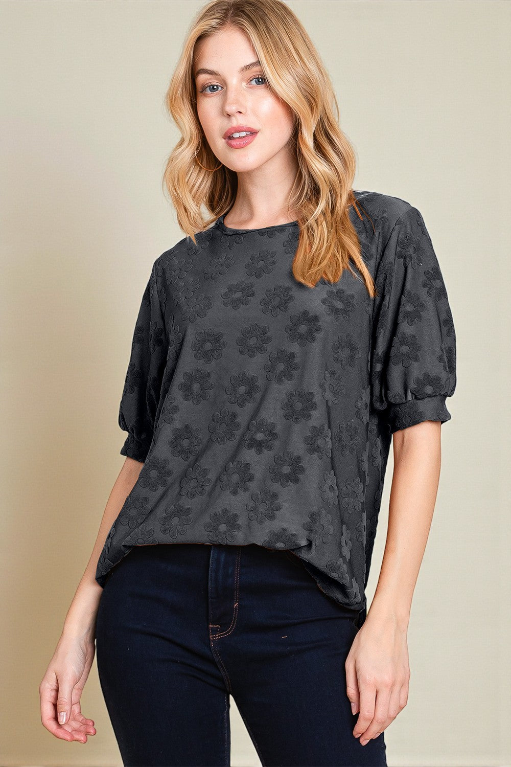 Woman wearing a dark floral patterned top against a beige background