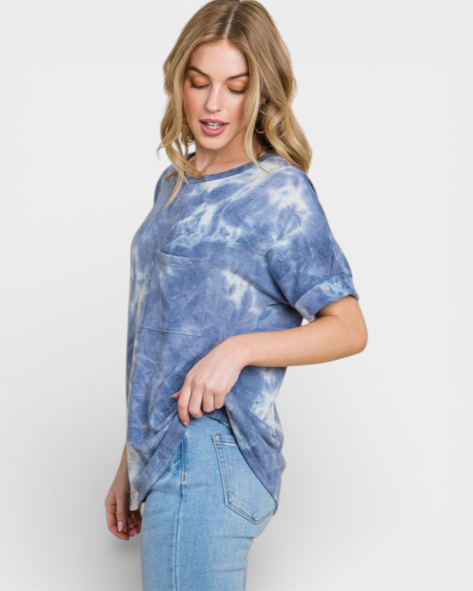 Woman wearing a blue tie-dye shirt and jeans on a white background