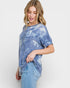 Woman wearing a blue tie-dye shirt and jeans on a white background