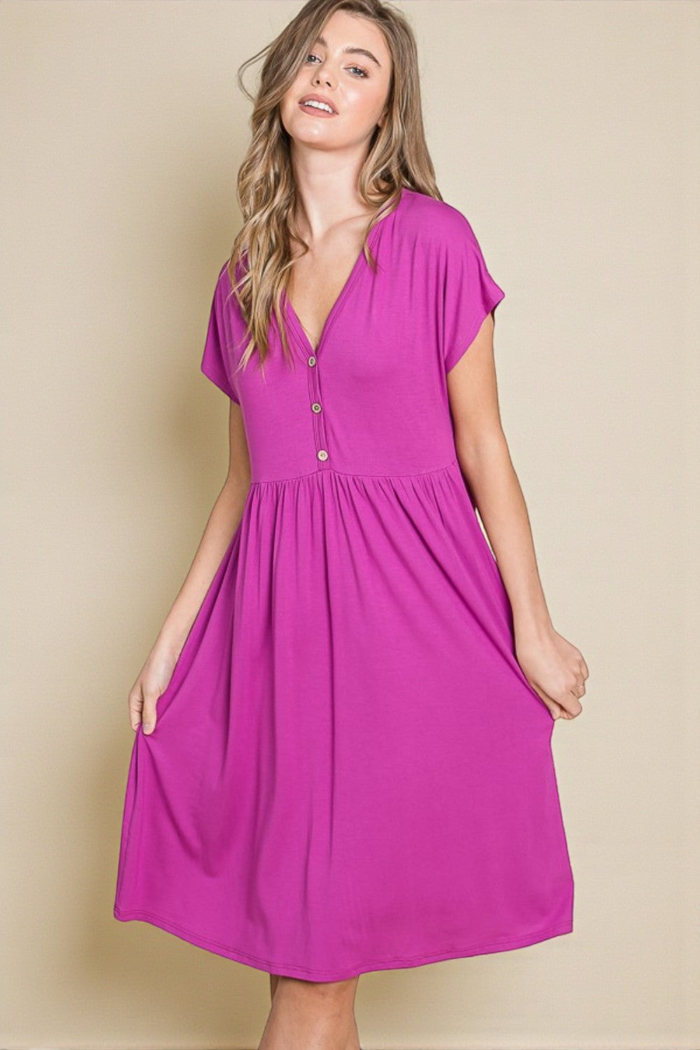 Woman wearing a pink dress against a beige background