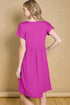 Woman wearing a bright pink dress against a beige wall.