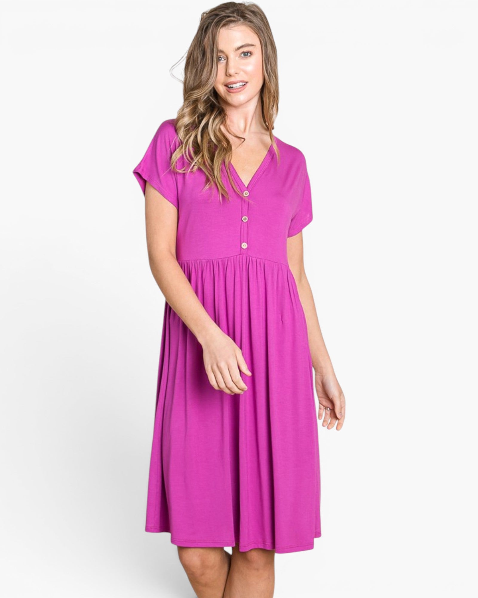 A woman modeling a bright magenta short-sleeve V-neck dress with a buttoned chest and a flared skirt, photographed against a clean white studio background.