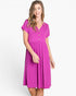 A woman modeling a bright magenta short-sleeve V-neck dress with a buttoned chest and a flared skirt, photographed against a clean white studio background.
