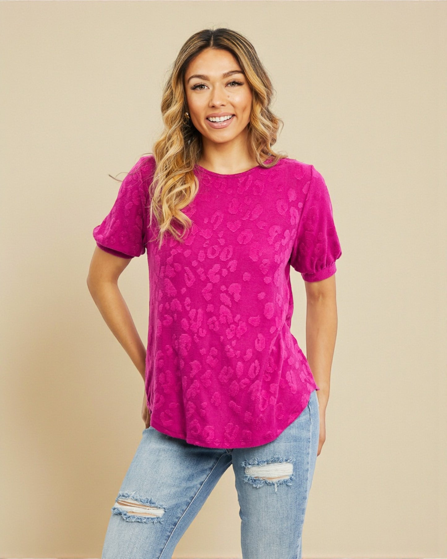Woman wearing a pink patterned top and blue jeans on a beige background