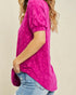 Person wearing a bright pink floral blouse with blue jeans on a beige background
