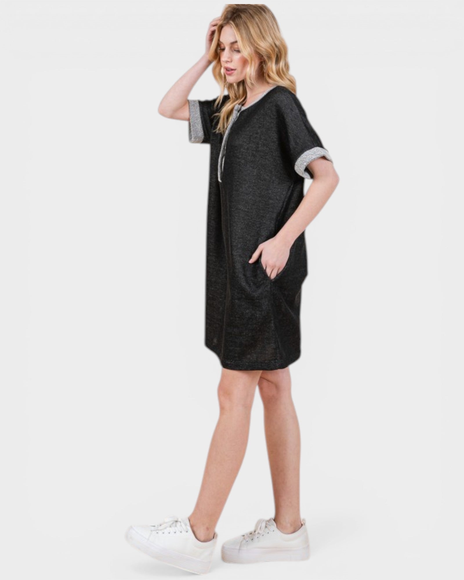 Woman wearing a black dress with white sneakers on a white background