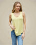 Woman wearing a yellow tank top and blue jeans on a beige background