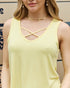 Woman wearing a yellow tank top with criss-cross straps in front.