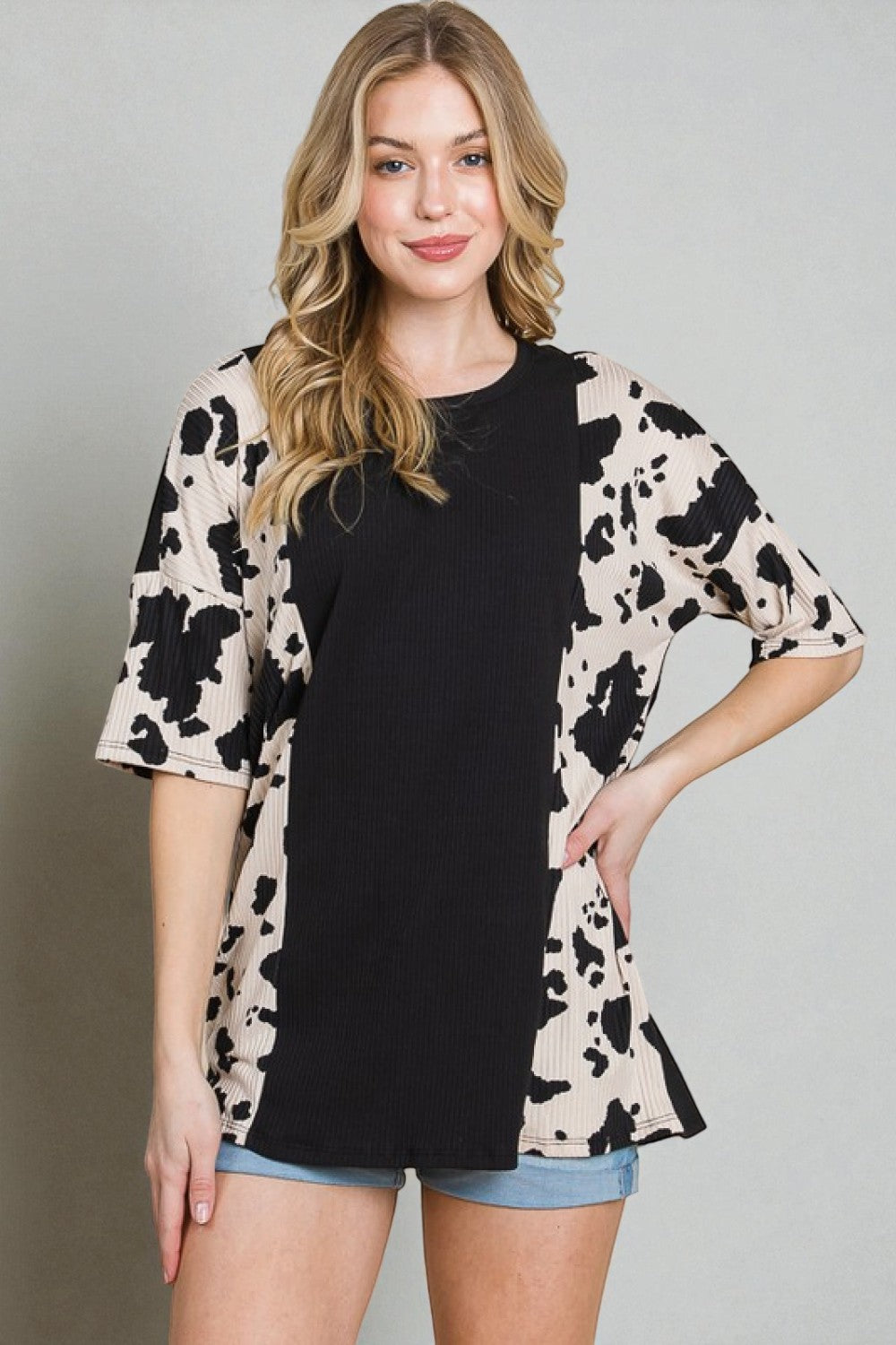 Woman wearing a black top with a floral kimono-style jacket against a gray background