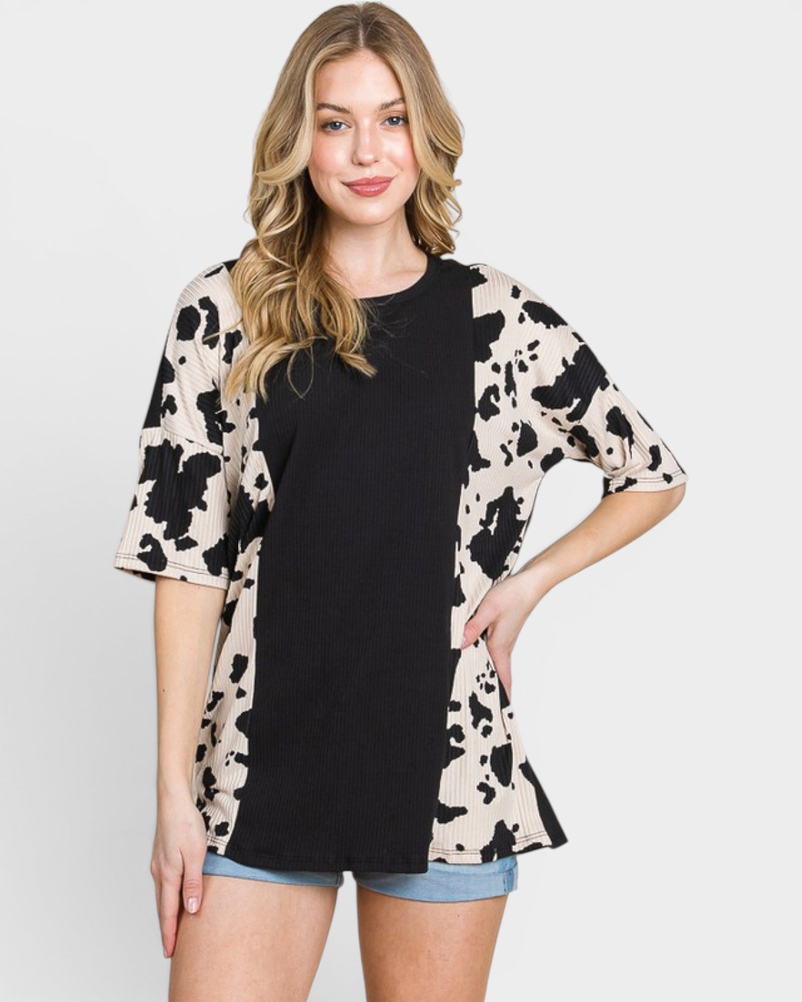 Woman wearing a black top and a beige cardigan with black patterns on a white background
