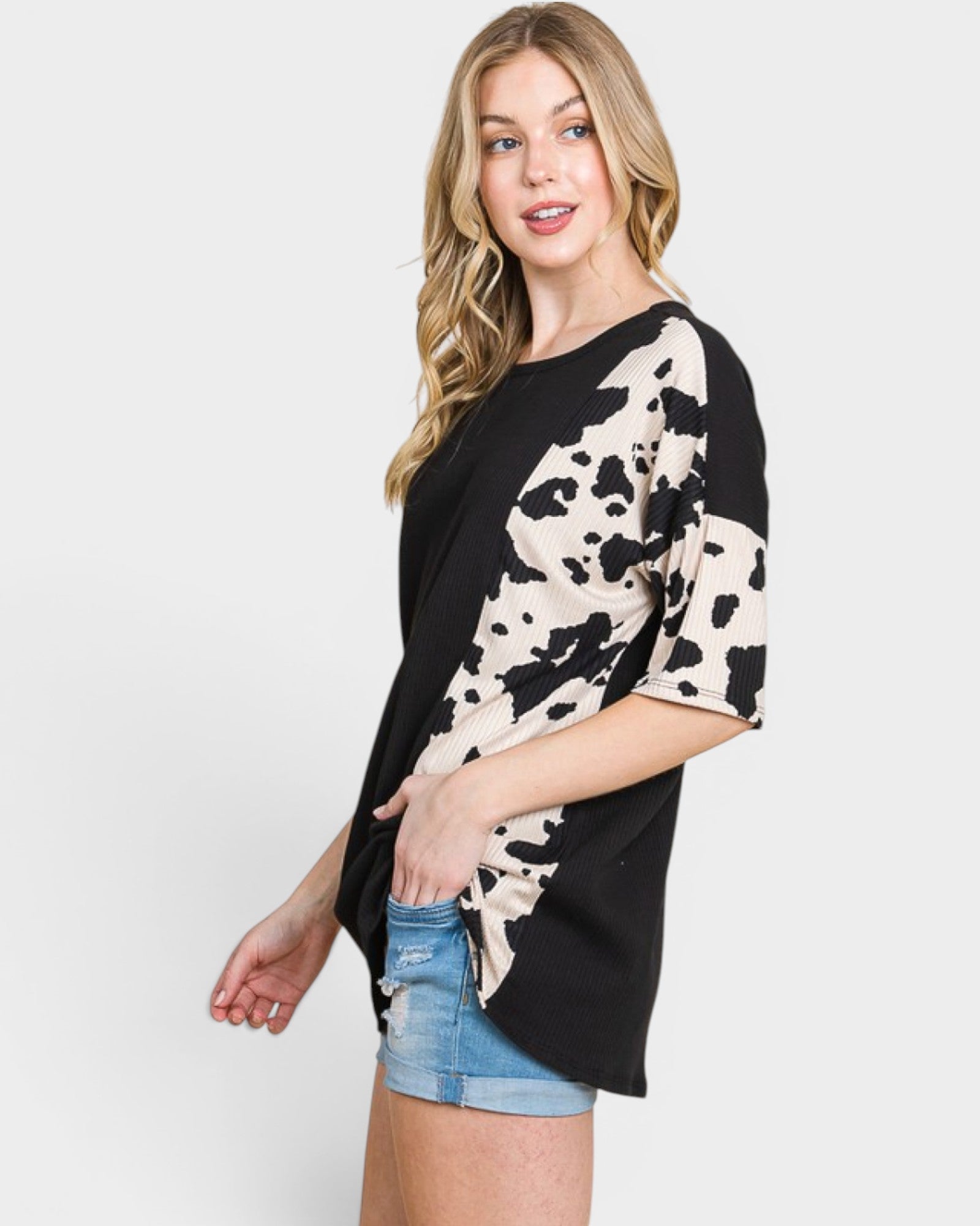 Woman wearing a black and white patterned top with denim shorts on a white background