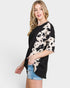 Woman wearing a black and white patterned top with denim shorts on a white background