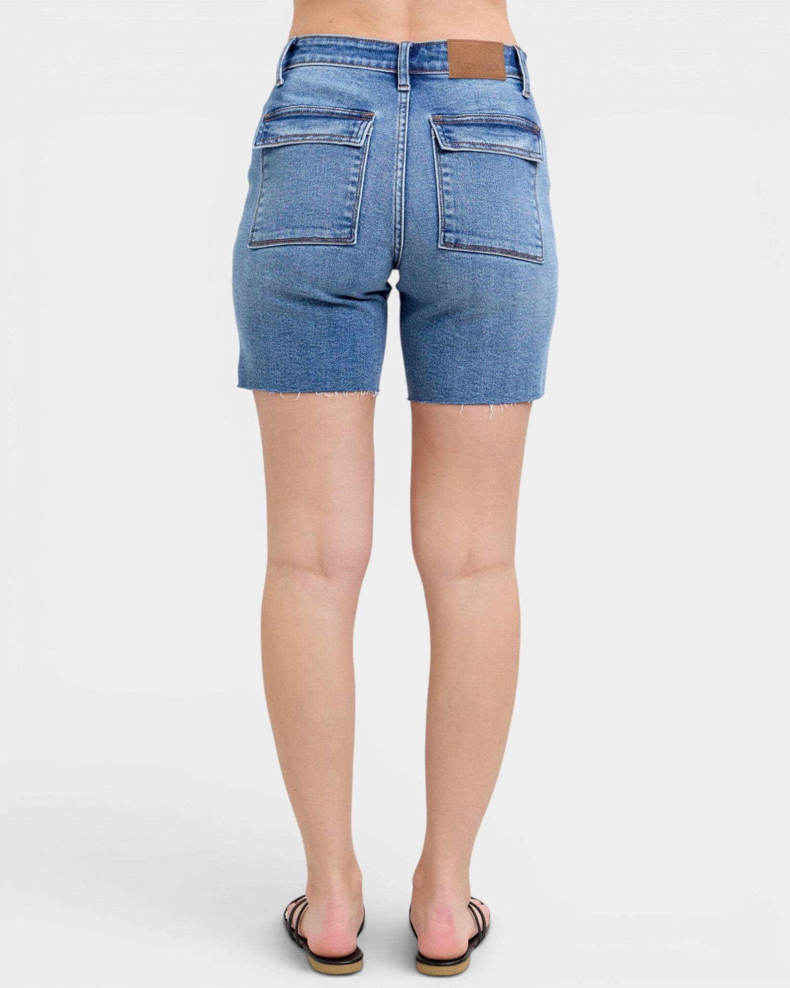 Blue denim shorts worn by a person on a white background