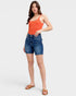 Woman wearing an orange top and blue denim shorts on a white background