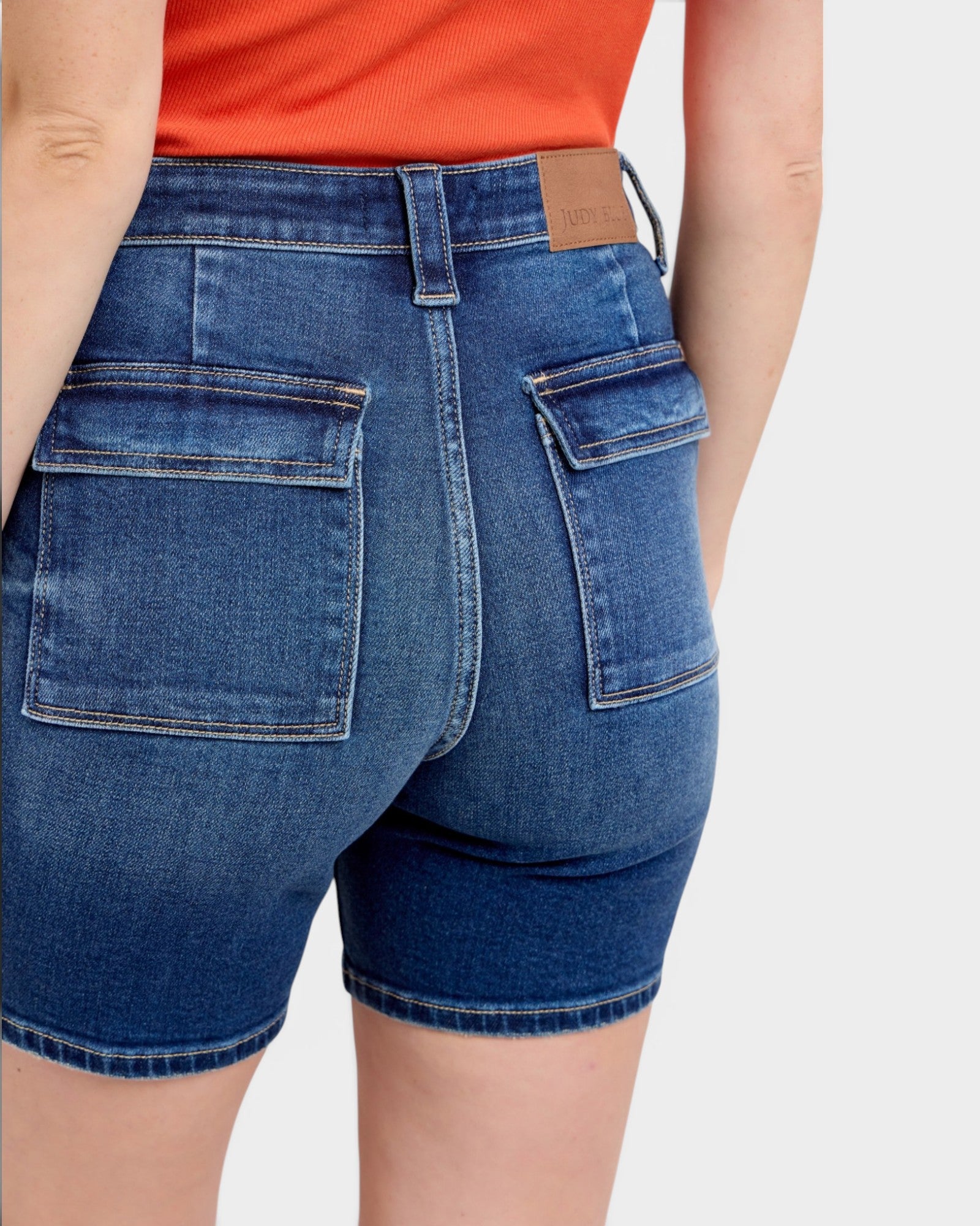 Blue denim shorts worn by a person on a white background