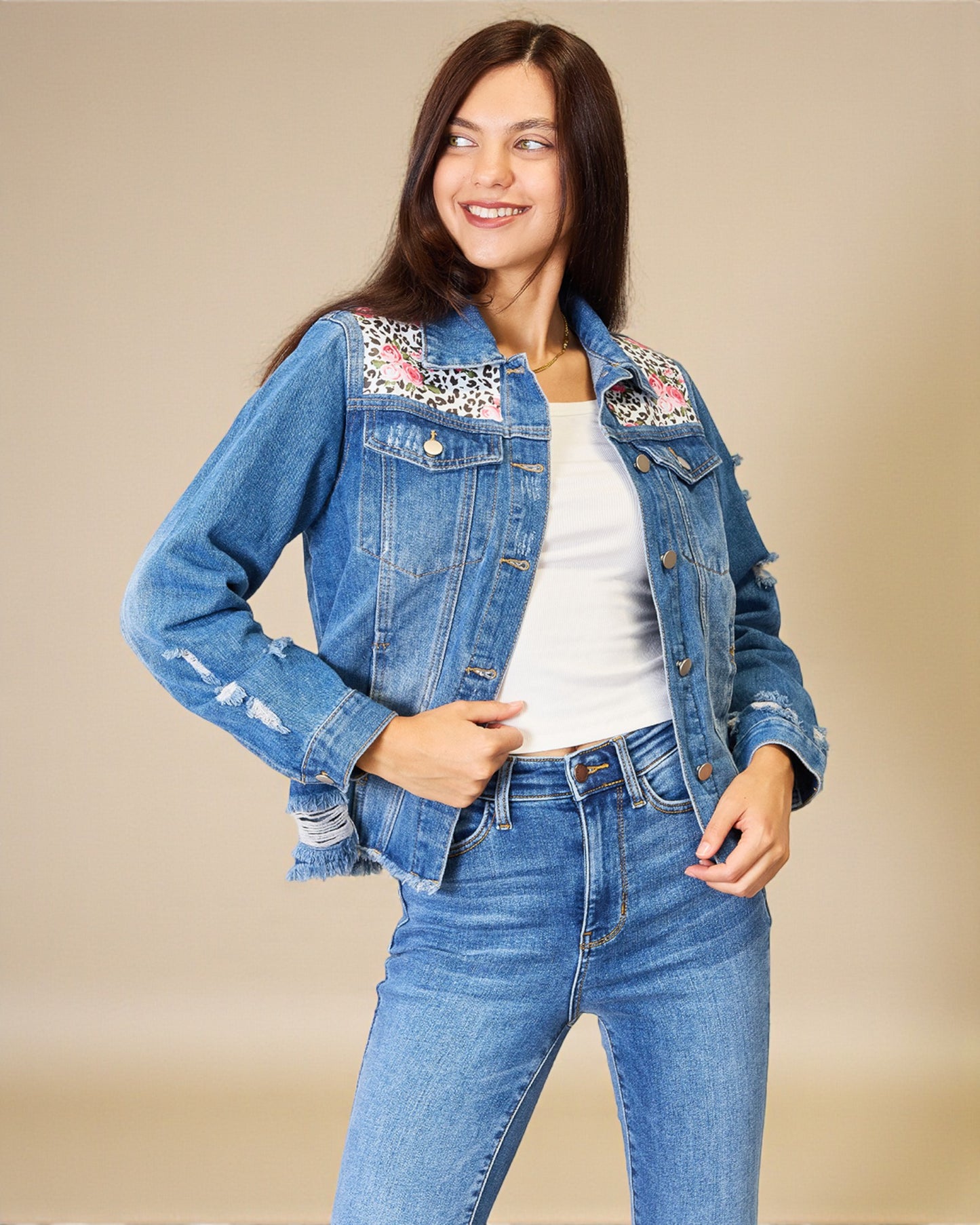 Woman wearing a denim jacket with floral embroidery on a beige background