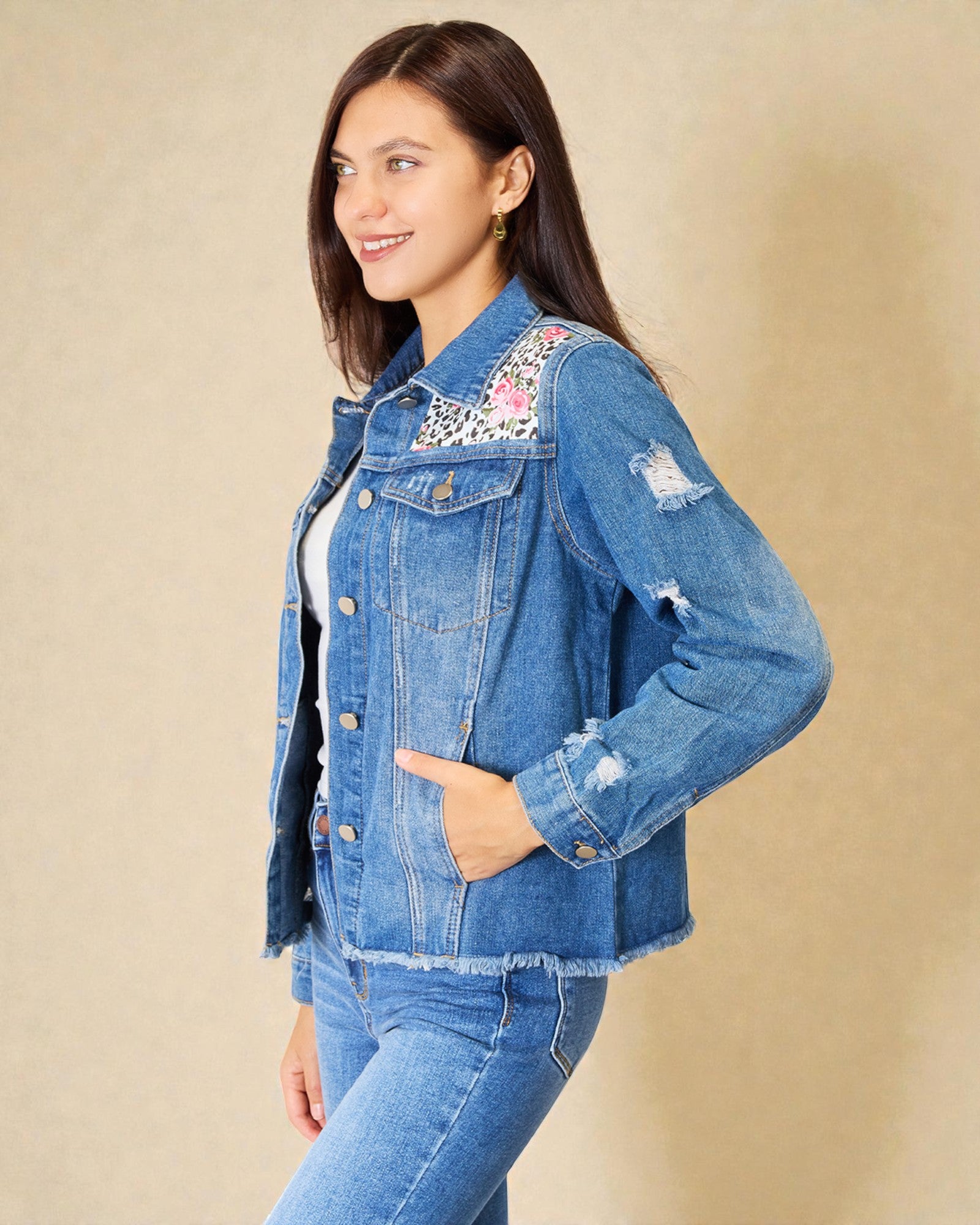 Woman wearing a blue denim jacket with floral embroidery on a beige background