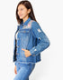 A woman wearing a distressed blue denim jacket with floral and leopard print embroidery on the chest, paired with blue jeans, against a plain white background.