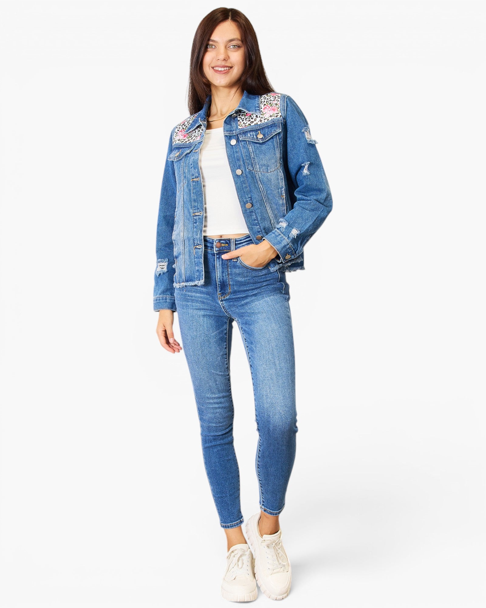 A woman modeling a light blue denim jacket with embroidered details on the shoulders and sleeves, paired with matching blue skinny jeans, a white top, and white sneakers against a plain white background.