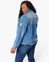 A woman wearing a light blue distressed denim jacket with frayed edges and ripped details, paired with dark blue jeans, shown from a side-back angle against a plain white background.