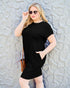 Woman wearing a black dress against a textured wall