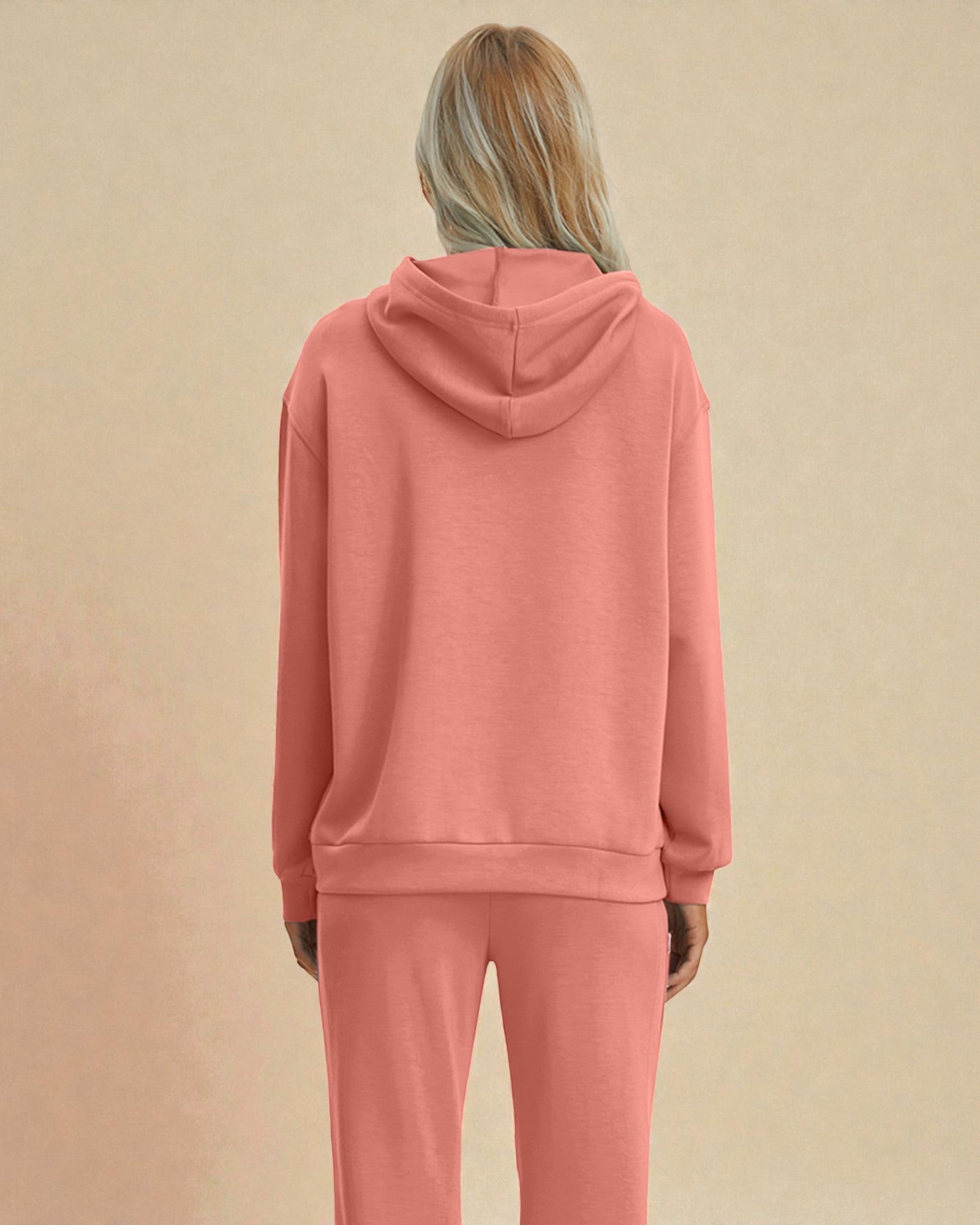 Person wearing a pink hoodie and pants on a beige background