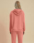 Person wearing a pink hoodie and pants on a beige background