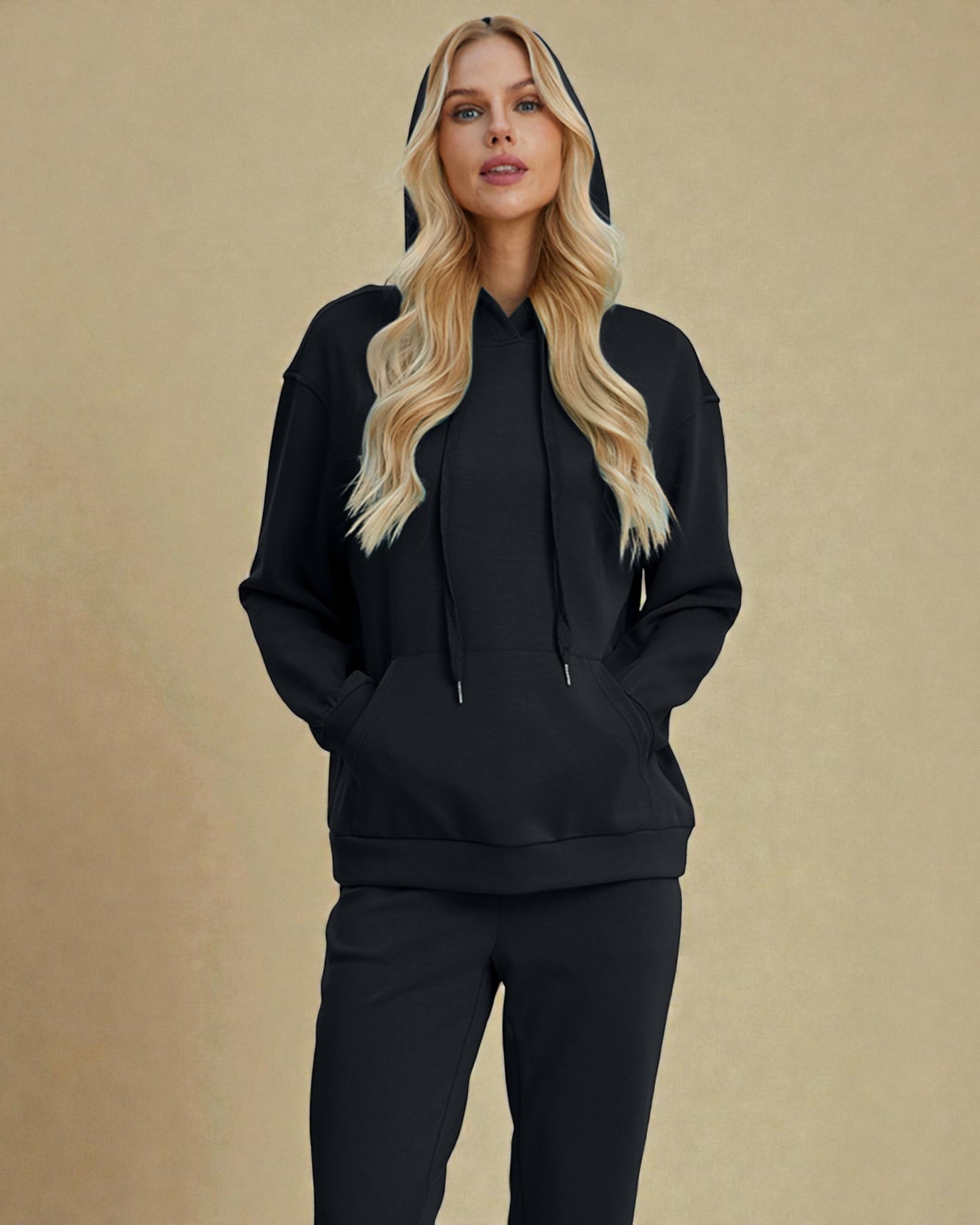Woman wearing a black hoodie and pants on a beige background