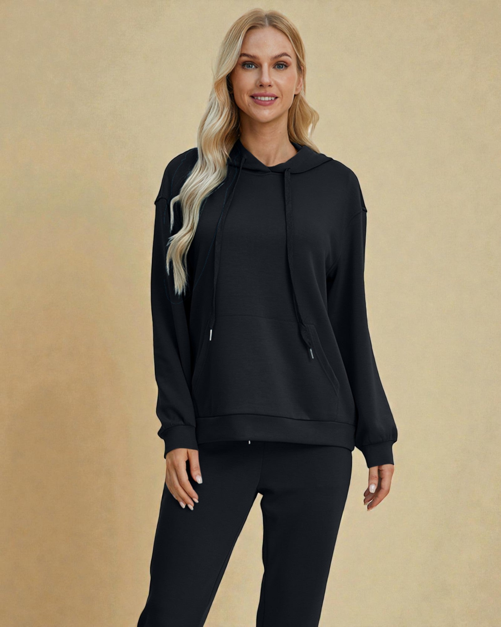 Woman wearing a black hoodie and pants on a beige background