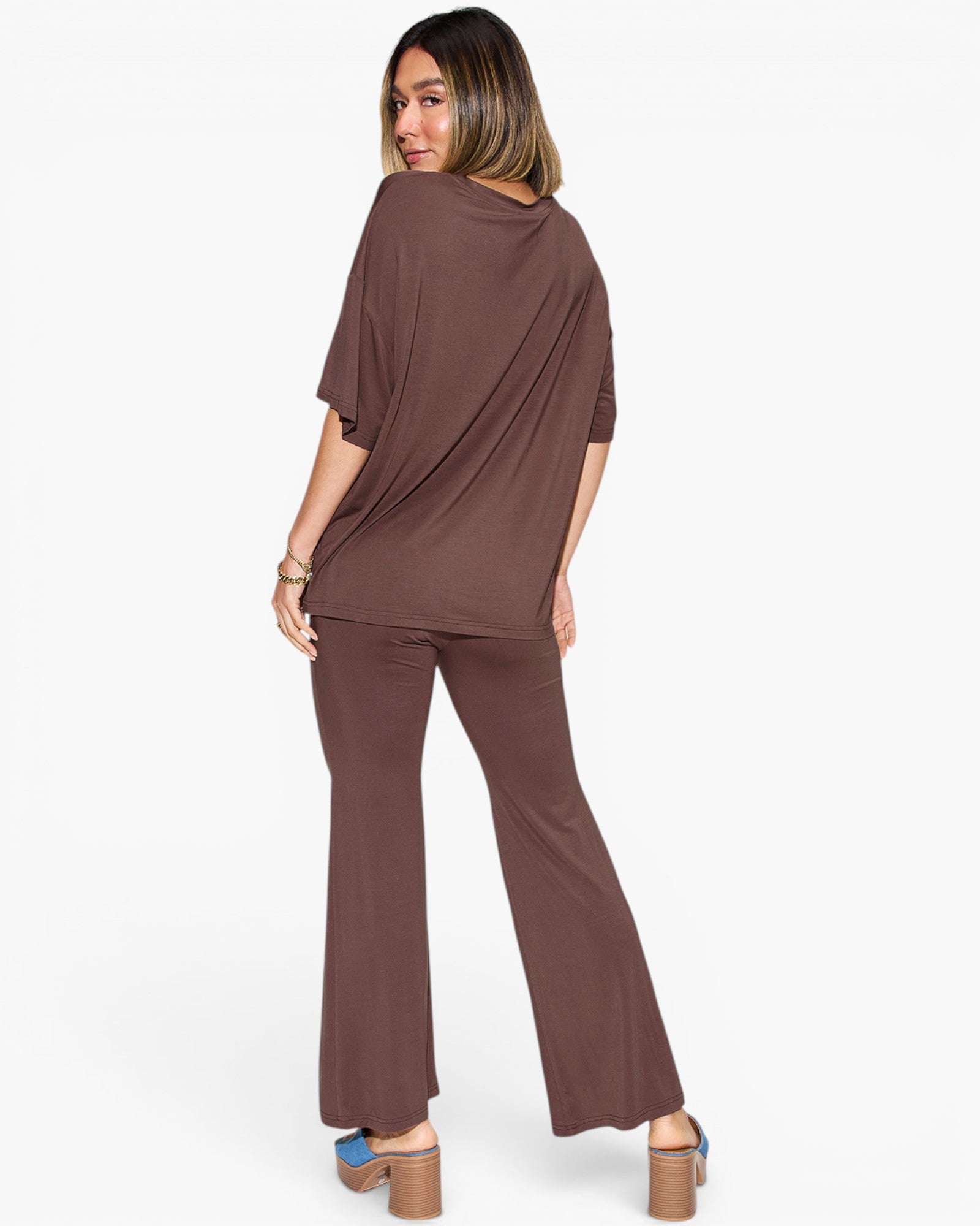 A woman modeling a matching two-piece lounge set in a solid brown color, featuring an oversized short-sleeve top and wide-leg pants, shown from a rear three-quarter angle against a plain white background.