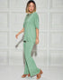 Woman wearing a green outfit against a white paneled wall
