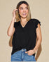 Woman wearing a black top and blue jeans against a beige background