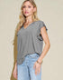 Woman wearing a gray ruffled sleeve top and blue jeans against a beige background