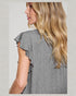 Woman wearing a gray ruffled sleeve top with a plain background