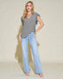 Woman wearing a gray ruffled blouse and light blue jeans against a beige background