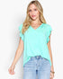 A woman modeling a mint green short-sleeve V-neck top with ruffle details on the sleeves, paired with light-wash blue jeans against a plain white background.