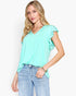 A woman modeling a mint green short-sleeve top with ruffled sleeves and light blue jeans against a plain white background.