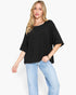A woman modeling a black short-sleeve top with a peplum waist detail, paired with light-wash blue jeans, against a plain white background.