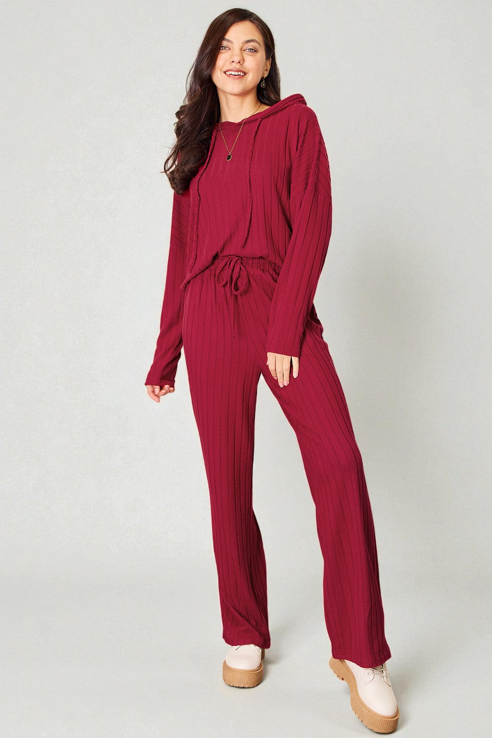 Woman wearing a burgundy tracksuit on a white background