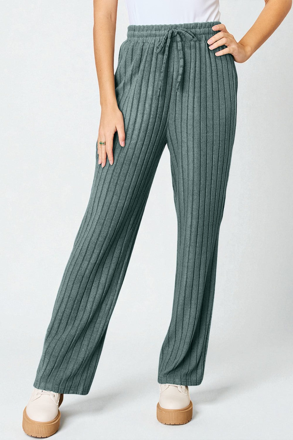 Green ribbed pants worn by a person on a white background