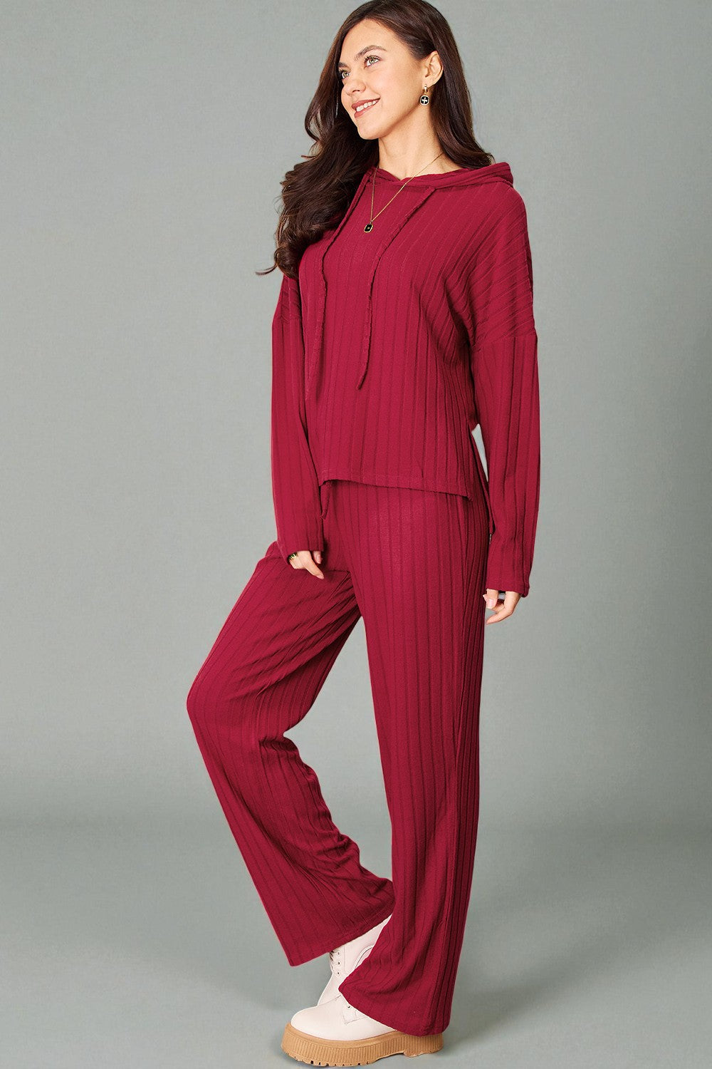 Woman wearing a burgundy outfit with a matching jacket and pants on a gray background