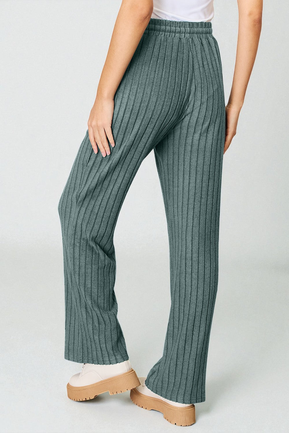 Green ribbed pants worn by a person on a white background