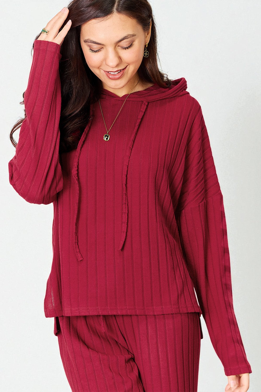 Woman wearing a burgundy outfit with a matching top and pants on a white background