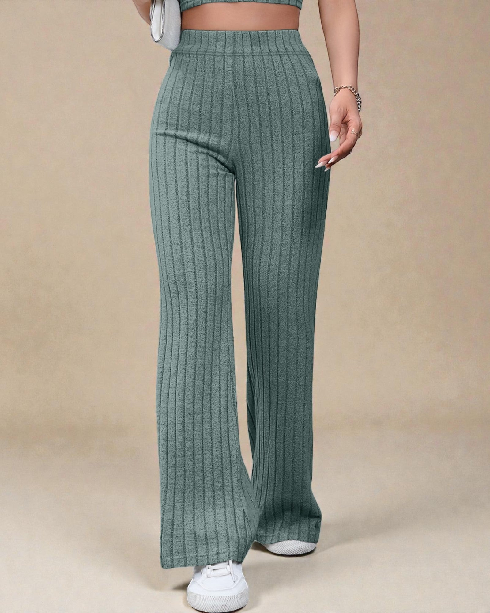 Green ribbed pants worn by a person on a beige background