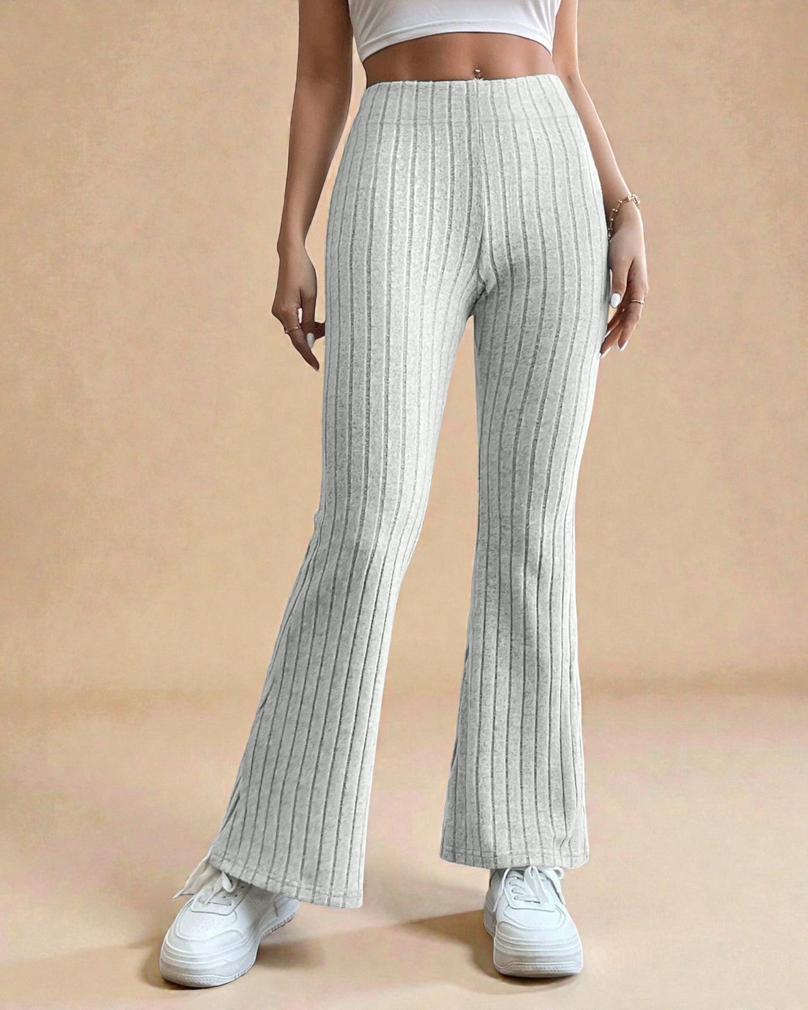 Person wearing light gray ribbed pants on a beige background